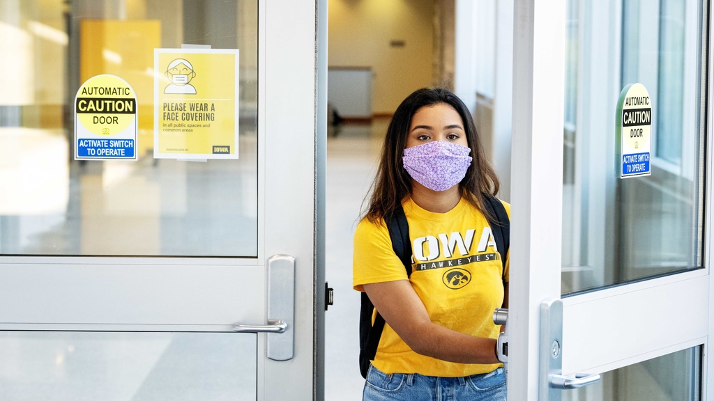 Student exiting building wearing facemask
