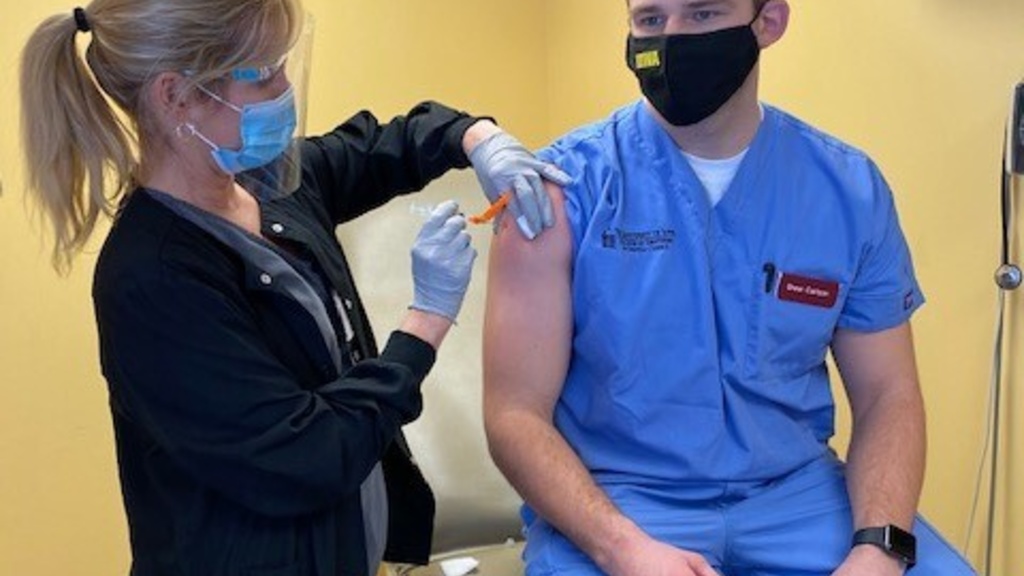 Assistant Nurse Manager Angie Lehman, RN BSN, administers the first dose of the COVID-19 vaccine to Drew Carlson, fourth-year student in the College of Dentistry.